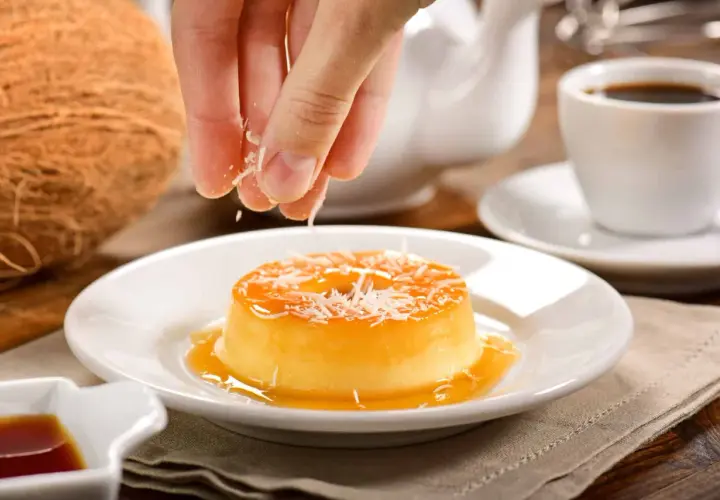 Un flan au lait de coco sans four, garni de noix de coco râpée, prêt à être dégusté avec un café.
