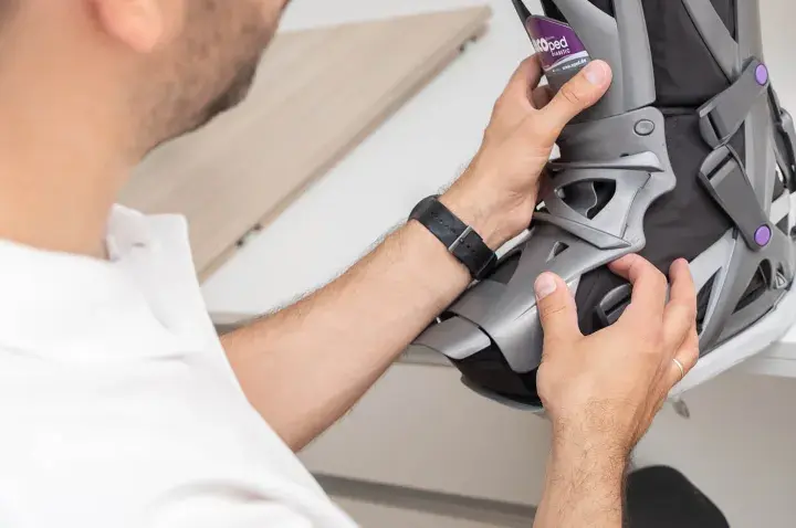 Mann mit weißem Poloshirt passt eine orthopädische Schiene an, die auf einem Rezept für orthopädische Schuhe basiert.