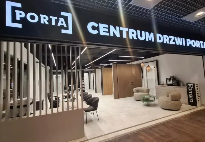 Salon drzwi i okien PORTA z ekspozycją drzwi, meblami i ekspressem do kawy.