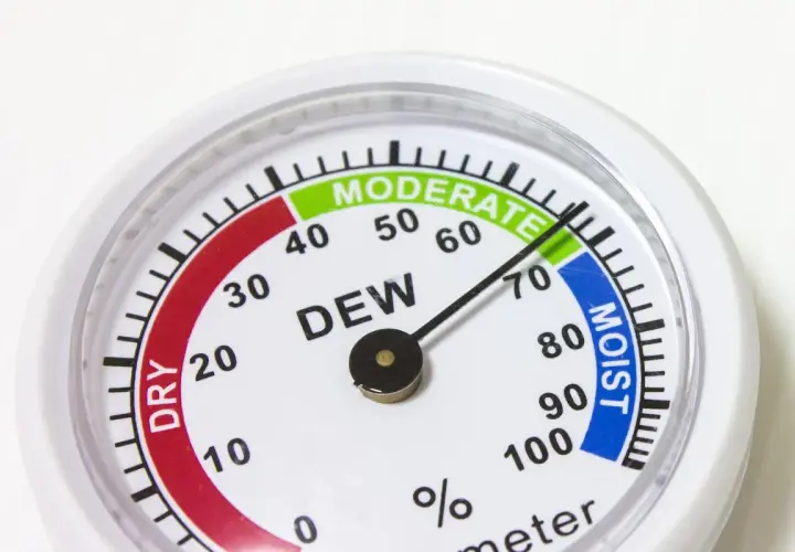 Un higrómetro que mide la humedad del aire, con zonas indicadas como "DRY", "MODERATE" y "MOIST".