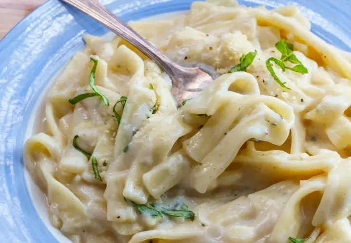 Pyszny makaron z tuńczykiem w sosie śmietanowo-serowym, udekorowany świeżą bazylią i parmezanem. Idealny na szybki obiad.