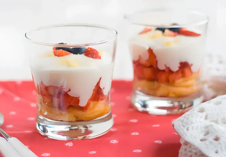 Delicioso tiramisú de fresa en capas, con bizcocho, fresas, crema y arándanos.