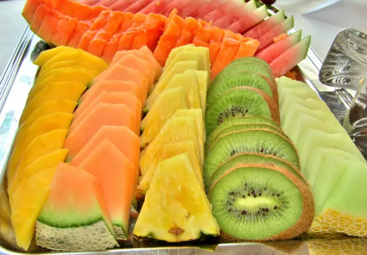 Présentation de fruits pour mariage : plateau coloré de pastèque, melon, papaye, ananas et kiwi coupés en éventail.