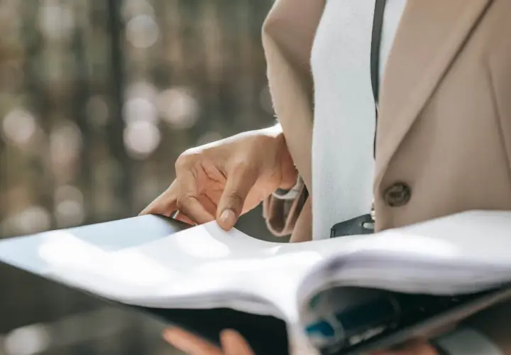 Dłoń przegląda dokumenty, przygotowując uruchomienie kredytu hipotecznego.