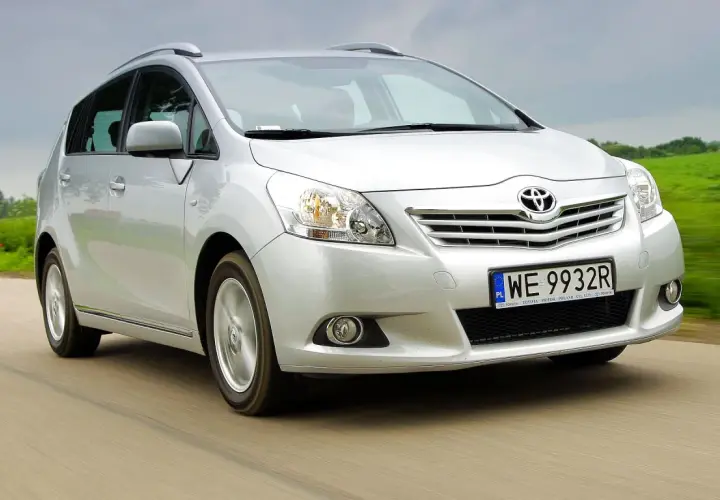 Srebrna Toyota Verso 1.8 benzyna w ruchu, z zielonym polem w tle.