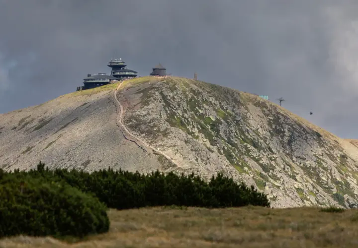 Schronisko i obserwatorium na szczycie w Karkonoszach, z widoczną kolejką linową i kamienistym zboczem.