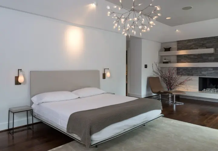 Camera da letto moderna con letto king-size, camino in pietra e un'elegante controsoffittatura che valorizza il design.