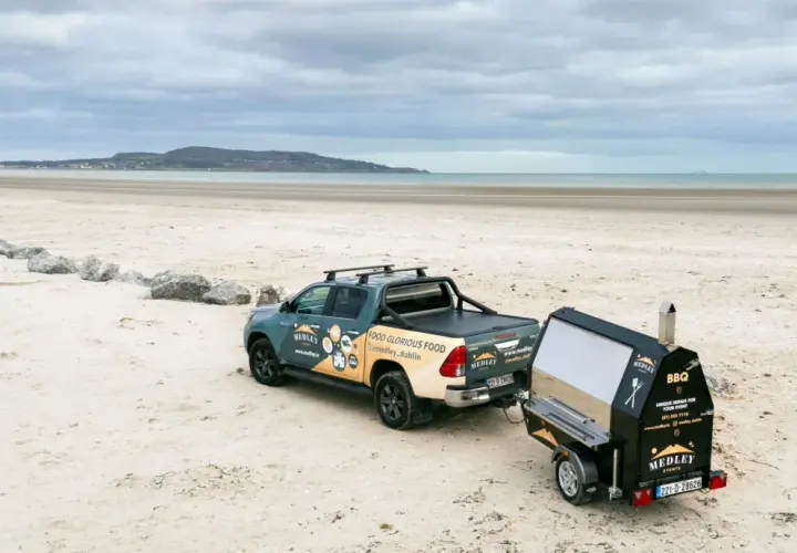 Un pick-up tracte un barbecue sur remorque sur une plage. Idéal pour fabriquer un barbecue sur remorque pour un événement en bord de mer.