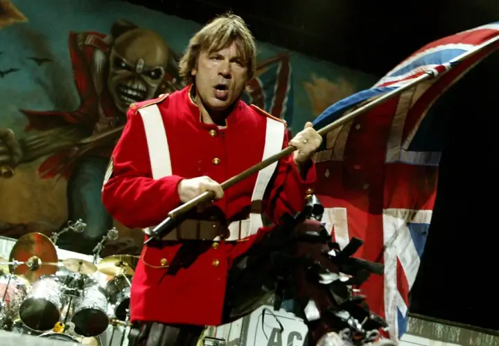 Bruce Dickinson z zespołu Iron Maiden na scenie z flagą Wielkiej Brytanii i Eddie'm w tle.