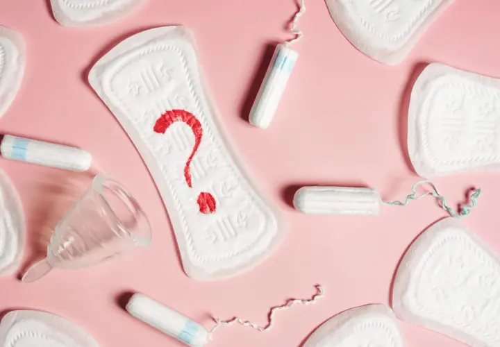 Plamienie 3 dni po okresie? Podpaski, tampony i kubeczek menstruacyjny na różowym tle.