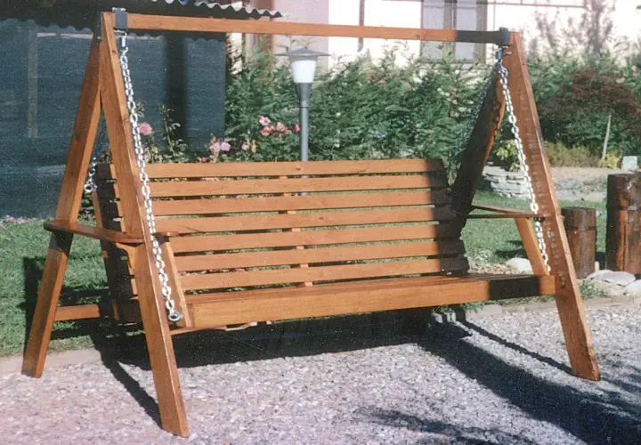Un dondolo in legno fai da te, con seduta a doghe, è pronto per rilassarsi in giardino.