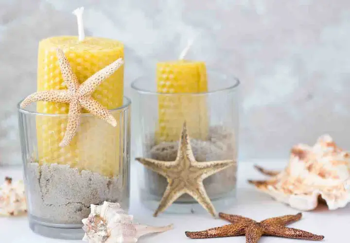Candelabri fai da te con candele gialle, sabbia e stelle marine in bicchieri di vetro. Un tocco marino per la tua casa.