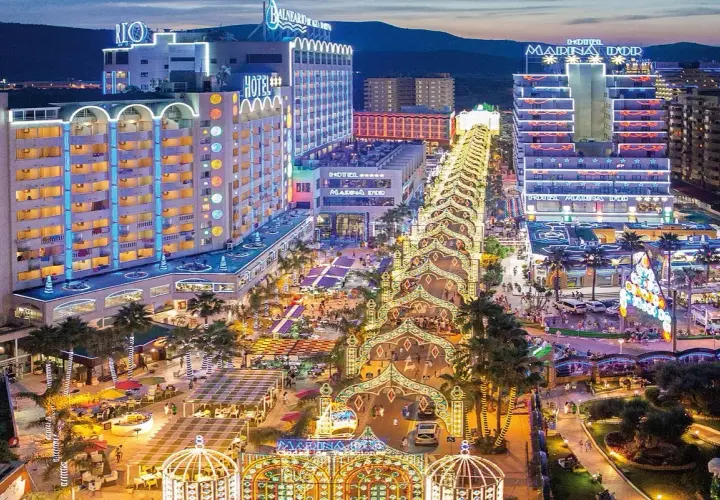 Noche vibrante en Marina d'Or, ciudad de vacaciones, con hoteles iluminados y un paseo lleno de luces y gente.