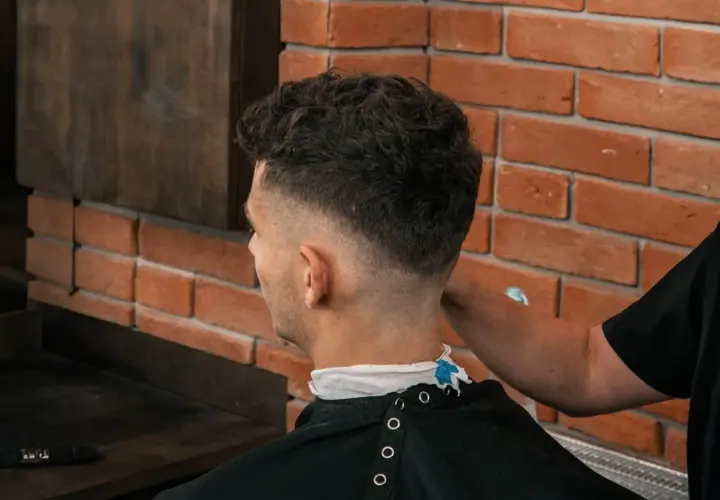 Mężczyzna z modną fryzurą fade, której nadano objętość za pomocą prestyler do włosów.