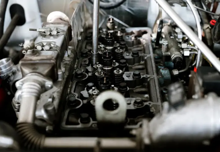 Silnik z widocznymi zaworami i wtryskiwaczami. Mechanik bada potencjalne przyczyny spalania stukowego, analizując stan elementów.