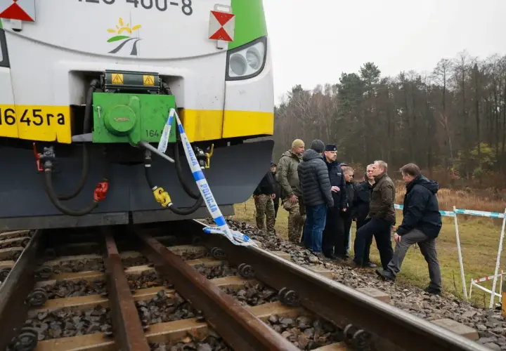 Grupa osób, w tym policjanci, ogląda przód lokomotywy EU07 005, otoczony taśmą policyjną.