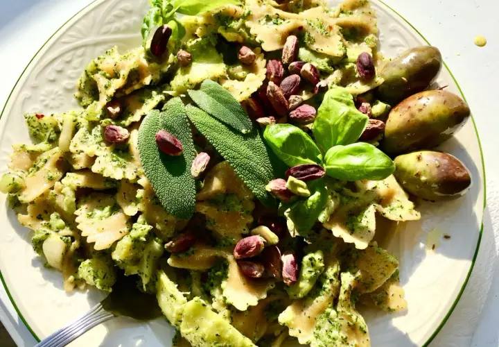 Farfalle condite con un saporito pesto di salvia, pistacchi e basilico fresco, guarnite con olive verdi.