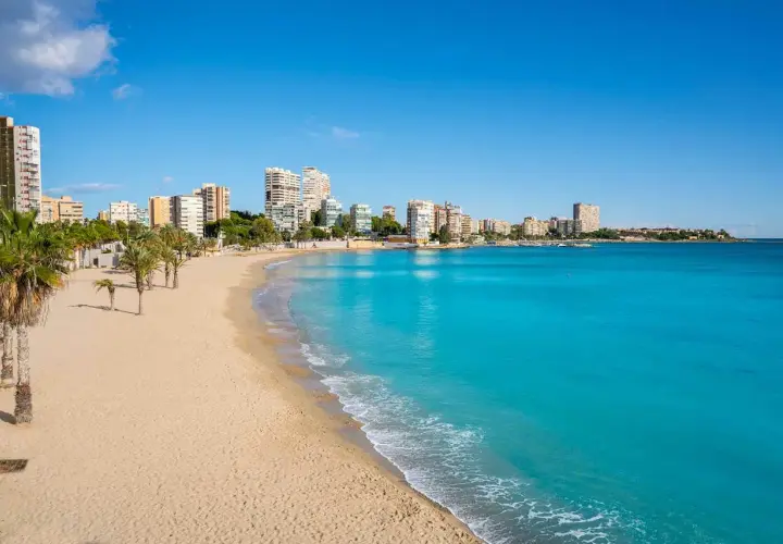 Playa de Oropesa del Mar con edificios y palmeras. Imagina tomar el tren Madrid Oropesa del Mar para llegar a este paraíso.
