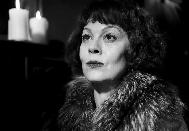 Helen McCrory, znana z roli Narcyzy Malfoy w Harry Potter, w eleganckim futrze i przy świecach.