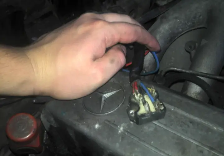 Ręka majstruje przy kostce elektrycznej, by sprawdzić wentylator nawiewu na krótko. Widoczny przekaźnik i przewody.