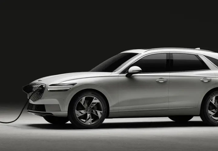 Biały Genesis GV70 na ładowarce. Elegancki SUV z charakterystycznym grillem i światłami LED.