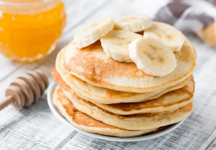 Pancake perfetti, dorati e soffici, preparati con la friggitrice ad aria, guarniti con fette di banana e miele.