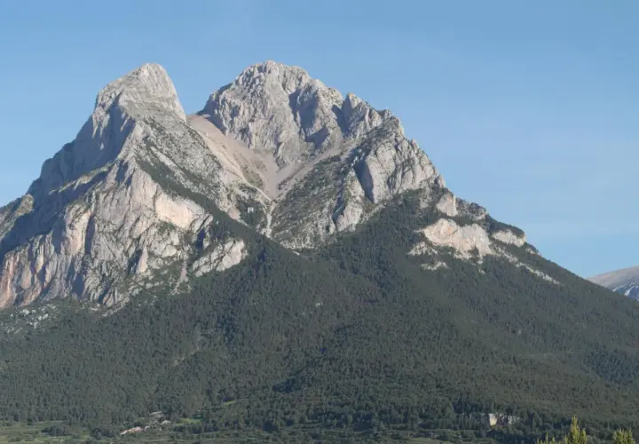 Majestuoso Pedraforca, cumbre rocosa coronada por pinos. Una ruta de senderismo desafiante espera.