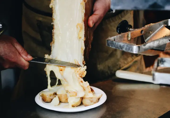 Un morceau de fromage à raclette classique fond sur des pommes de terre. Le fromage dégouline, prêt à être servi.