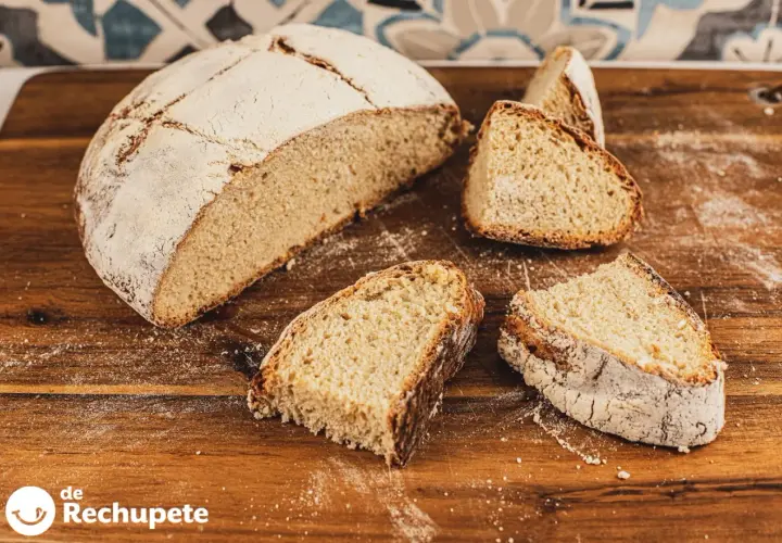 Un pan de papa casero, con su corteza dorada y miga esponjosa, cortado en rebanadas sobre una tabla de madera.