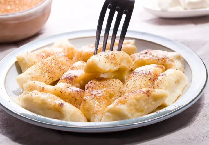 Pyszne pierogi leniwe posypane cynamonem, gotowe do jedzenia. Idealne na szybkie śniadanie lub deser.