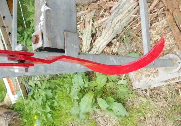 Roter, gebogener Metallarm, Teil eines Baumschiebers, der an einem Metallpfosten befestigt ist.