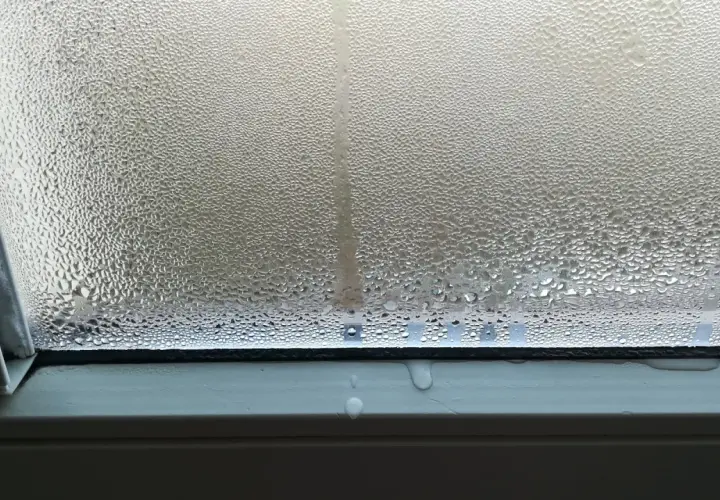 Goccioline d'acqua su un vetro, un fenomeno che illustra il concetto di traspirante significato, con condensa che scivola sul davanzale.