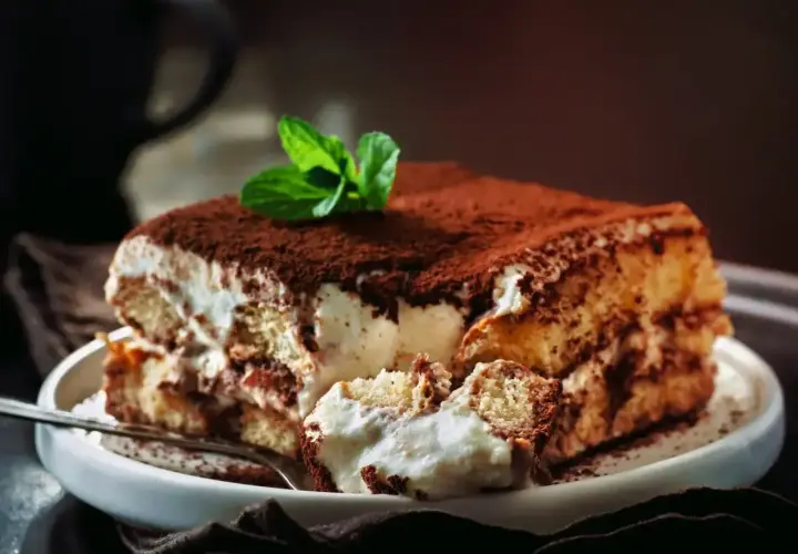 Pyszny, sprawdzony przepis na tiramisu z mascarpone. Kremowe warstwy biszkoptów i mascarpone, posypane kakao, z listkiem mięty.
