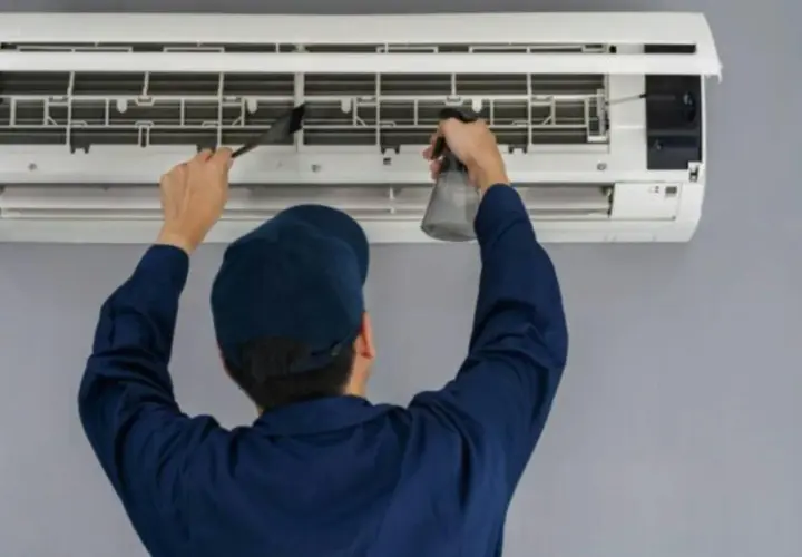 Técnico limpiando un aire acondicionado, paso clave para saber como se instala un aire acondicionado correctamente y mantenerlo.