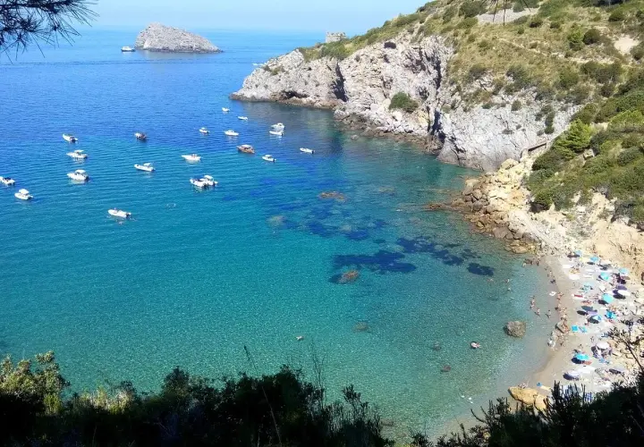 Ein **Geheimtipp Toskana Strand**: Türkisblaues Wasser, kleine Boote und ein sonniger Strand mit bunten Sonnenschirmen. Ein idyllischer Ort zum Entspannen.