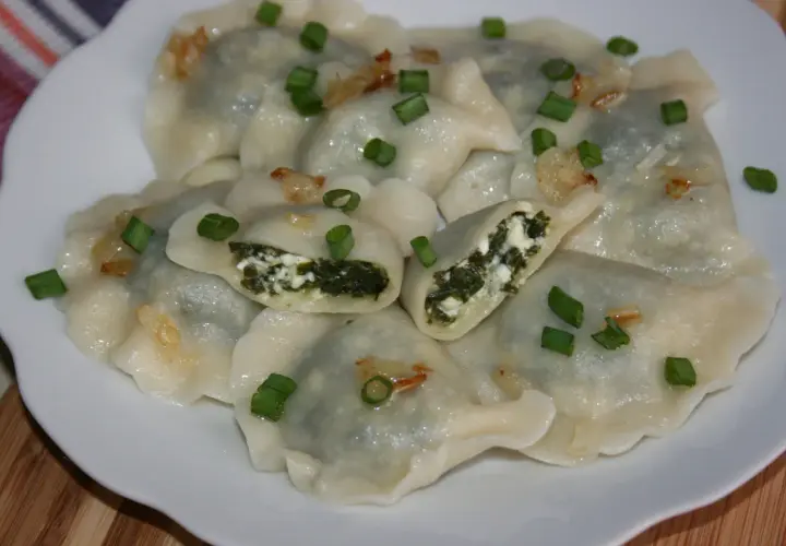 Pyszne pierogi ze szpinakiem i serem, posypane szczypiorkiem i skwarkami. Idealne na obiad!