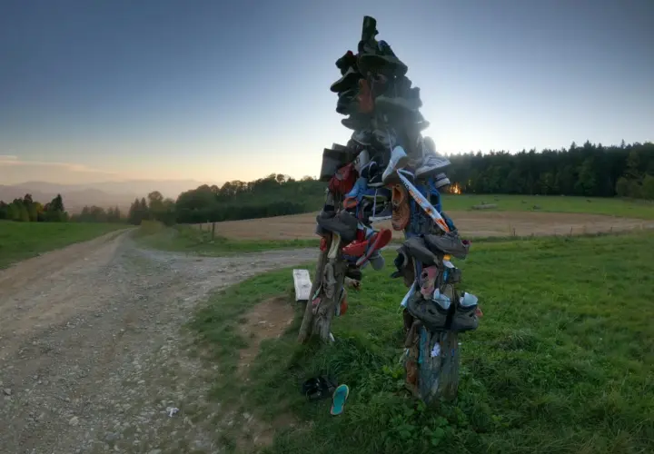 Skopiec szczyt. Rzeźba z butów na szczycie wzgórza, obok polnej drogi, o zachodzie słońca.