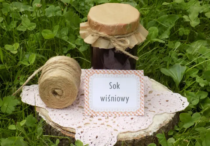 Sok z wiśni przepis: słoik domowego soku, sznurek i serwetka na pniu drewna. Idealny na lato!