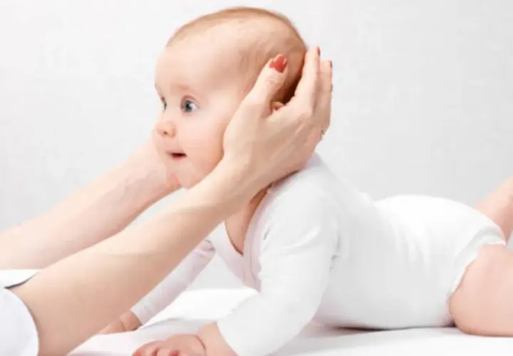 Manos sostienen la cabeza de un bebé que gatea. ¡Qué lindo mi bebe se pega en la cabeza!