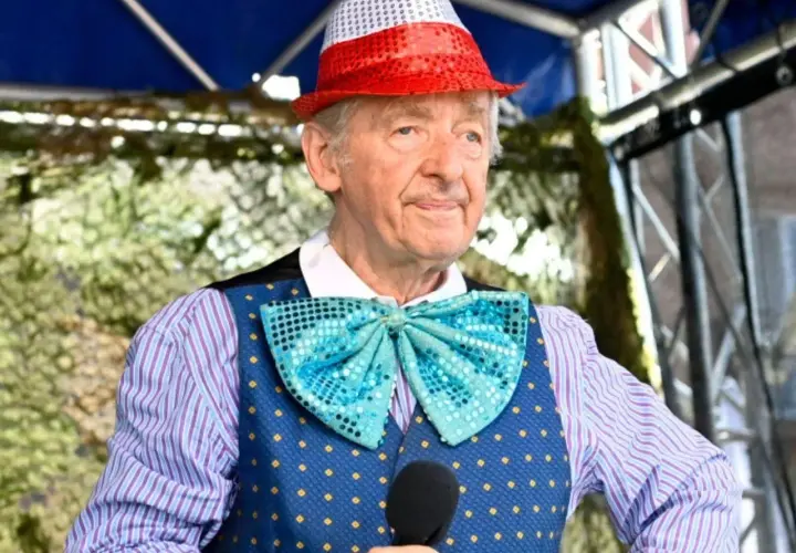 Uśmiechnięty Andrzej Rosiewicz w cekinowym kapeluszu i muszce, trzymający mikrofon. Wiek artysty to 80 lat.