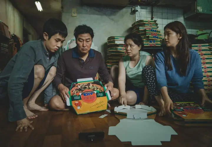 La famiglia Kim assembla scatole per pizza, una scena chiave nella **recensione** di "Parasite".