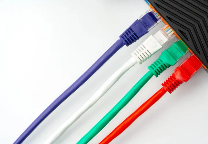 Cables de red de colores (morado, blanco, verde, rojo) conectados a un dispositivo.