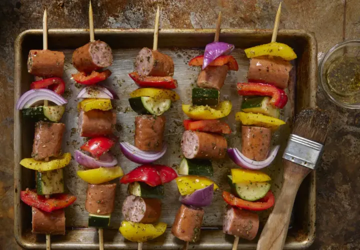 Spiedini di carne succulenta alternati a peperoni colorati, cipolla rossa e zucchine, pronti per essere grigliati.