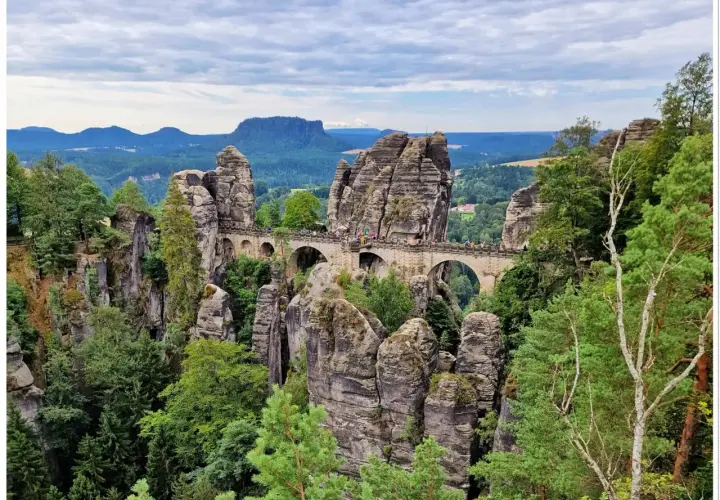Kamienny most Bastei w saksońskiej Szwajcarii, łączący skalne baszty. Widok na malowniczy krajobraz z lasami i wzgórzami.