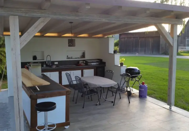 Gemütlicher **Grillplatz im Garten** mit überdachter Außenküche, Bartresen, Esstisch und Grill. Perfekt für gesellige Abende.