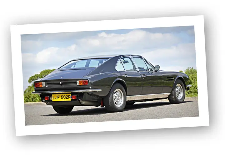 Klasyczny Aston Martin Lagonda z lat 70. na tle błękitnego nieba i zieleni.