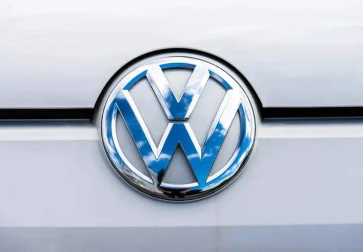 Das glänzende VW-Logo auf dem silbernen Lack reflektiert den blauen Himmel mit Wolken. Ein p0016 vw.