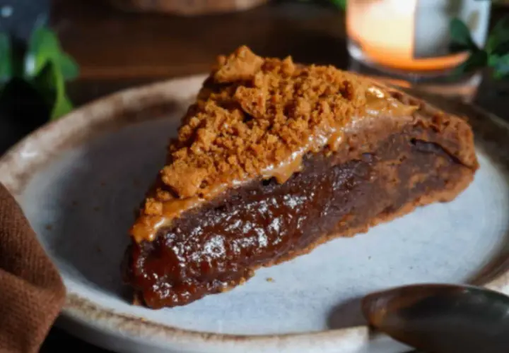 Une part de gâteau speculoos, riche et gourmande, garnie de miettes de biscuits et d'une sauce caramel.