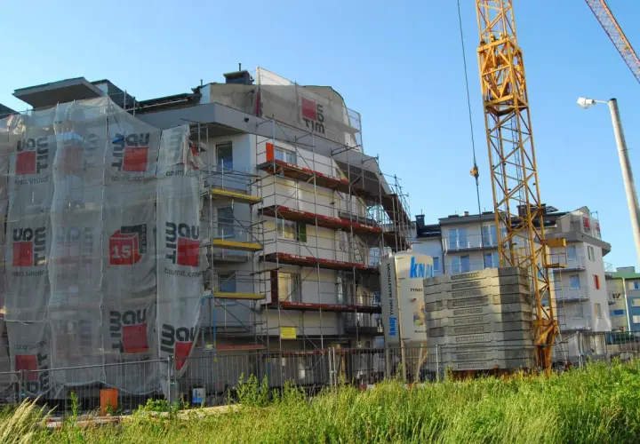 Budowa bloku mieszkalnego z żurawiem i rusztowaniami. Zastanawiasz się, ile deweloper zarabia na domu?