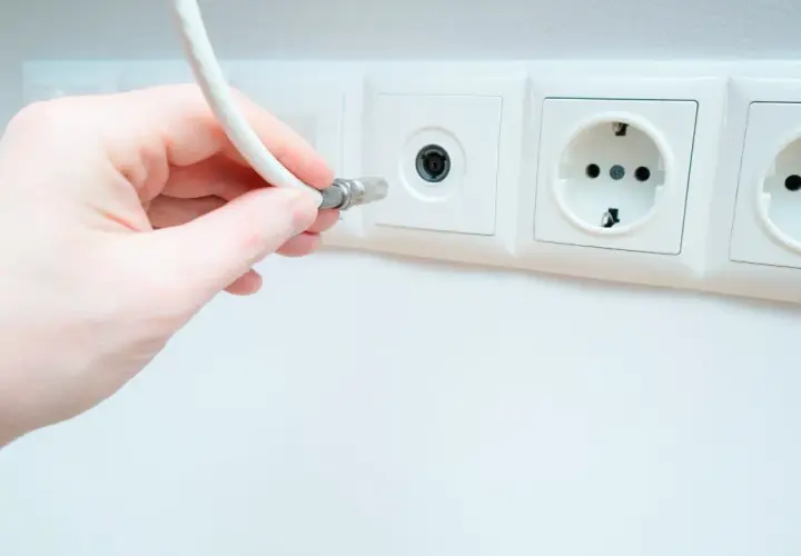 Dłoń podłącza kabel do gniazdka antenowego. Pytanie: jaki kabel do anteny naziemnej?